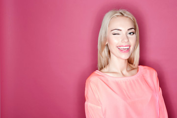 Fototapeta premium Pretty smiling girl winking on pink background