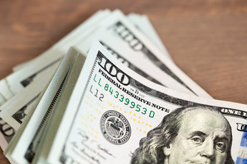 A pile of one hundred dollar bills on a table