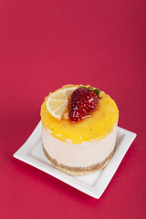 cheesecake with strawberry and lemon on red