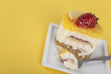 eating delicious cake with lemon and strawberry on yellow background