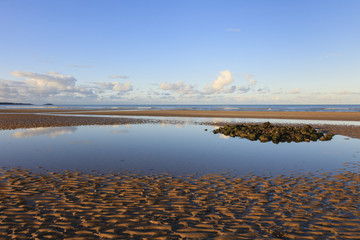 Tidal pool on Traeth Coch empty sandy beach at low tide in Red Wharf Bay, Isle of Anglesey, Wales, UK