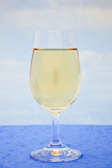 Glass of white wine with blue sky background