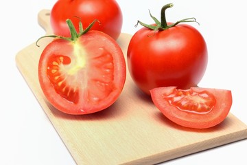 Pomodori rossi su un tagliere tagliati a meta e a spicchi, uno intero