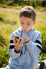 young boy looking at gps while geocaching