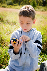 young boy looking at gps while geocaching