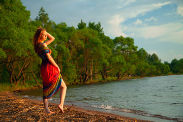 Girl in dress walking on the sea coast in the trees along the sa