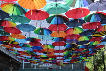 Fototapeta na wymiar Under a rainbow of umbrellas. Soaring in the sky multi-colored umbrellas.