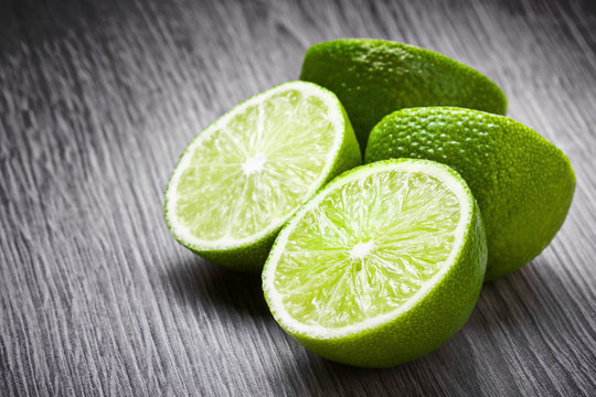 Fresh limes cut in half on wooden surface