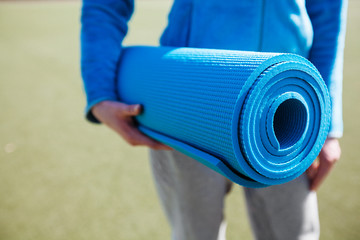 A woman walking with a yoga mat