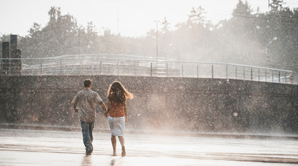 cople in love hugging and kissing under summer rain