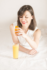 Happy young woman with glass of fresh orange juice, studio shot on white