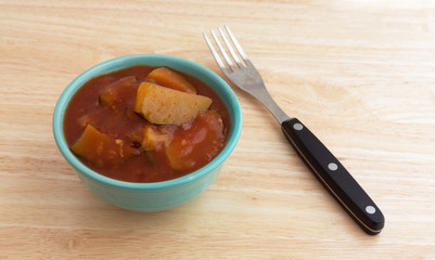 Chunks of zucchini in tomato sauce in bowl plus fork