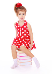 Beautiful Caucasian girl in a red dress with polka dots sitting 