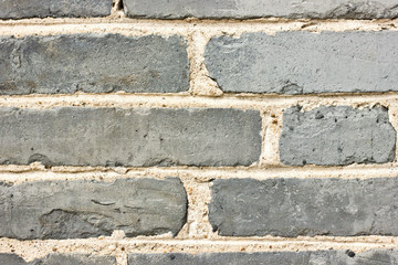 Grunge brick wall texture. Aged gray bricks with weathered surface and white mortar. Urban building detail for background. Suitable for construction, architecture, restoration or retro design.