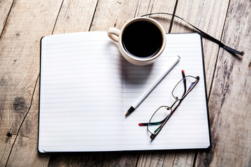 glasses on notebook with pen and cup