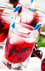 Cherry red drink with ice in a heart shape, selective focus