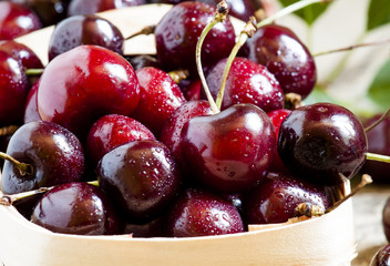 Dark red ripe cherries in a wicker basket, selective focus