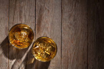 Glasses of whiskey with ice on wood