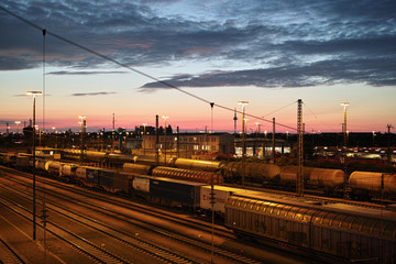 Obraz na płótnie Canvas Sonnenuntergang am Rangierbahnhof mit Zügen, Waggons, Gütern