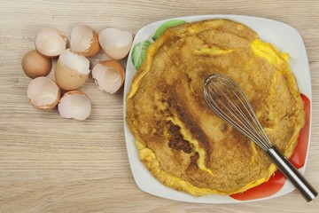 Scrambled egg omelet on a wooden table. A plate of food.
