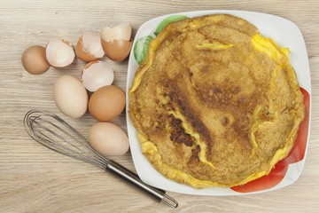Scrambled egg omelet on a wooden table. A plate of food.
