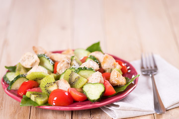 Salad with tomatoes cucumber  kiwi and chicken
