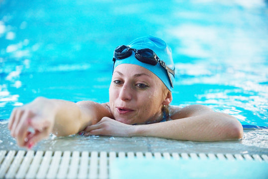 woman swimmer resting in the pool pointing