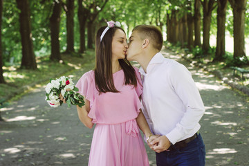 Newlyweds tseltsyutsya in the park. Bride is holding a bouquet of beautiful flowers