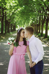 Naklejka premium Newlyweds tseltsyutsya in the park. Bride is holding a bouquet of beautiful flowers