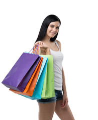 A happy brunette woman with the colourful shopping bags from the fancy shops. Isolated.
