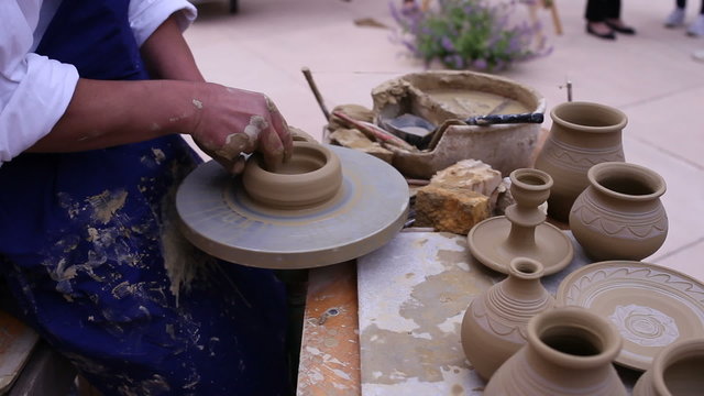Pottery maker uses a kick wheel to hand mold a pot from clay 