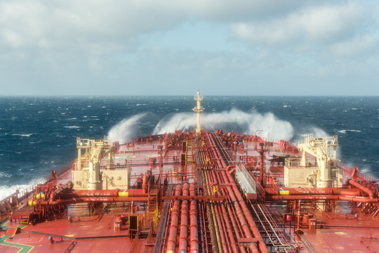 Oil tanker steering forward during stormy weather with breaking waves - stock photo