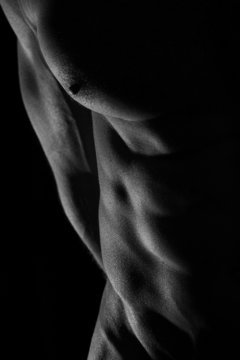 Close-up of perfect male body, low key image
