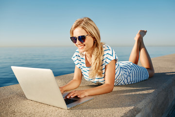 Cheerful girl lying at summer on the beach near sea and talks