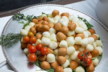 Piccole mozzarelle bicolori su piatto da portata rotondo e argentato