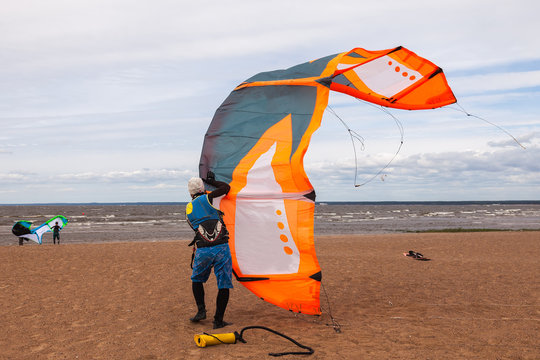 Kite surfer wearing a wetsuit is preparing his kite on a windy d