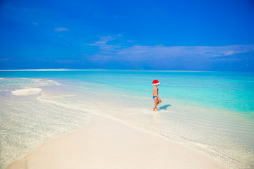 Little girl in Santa hat on the beach during vacation