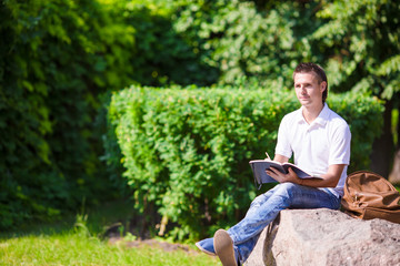 Young man studying for college exam in park outside