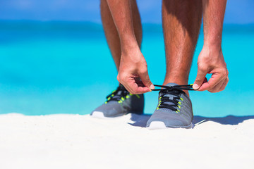 Young male runner getting ready to start on white beach