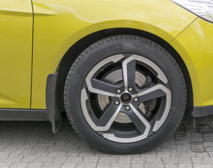 Fototapeta na wymiar Yellow car closeup - front wheel with light alloy rim