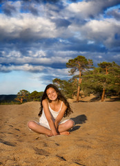 Fototapeta na wymiar Happy young woman in white sitting on the beach