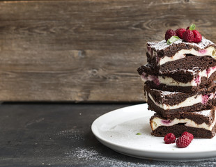 Brownies-cheesecake tower with raspberries on white plate
