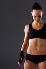 Muscular young woman  standing on gray background