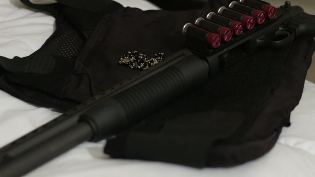 Man puts shotgun on bed with bulletproof vest