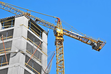 Crane and building construction site against blue sky