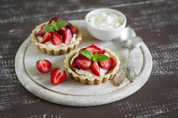 tartlets with cream cheese and strawberries on a light wooden background