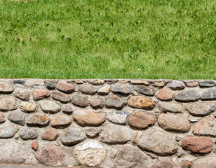 horizontal image of a two part image of the bottom half as a stone wall and top half green grass 