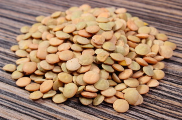 Heap of green lentil on wooden background