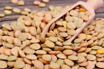 Heap of green lentil with spoon on wooden background