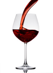 Red wine poured in a glass isolated on white